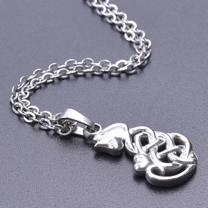 Macro shot of silver stainless steel cat-shaped pendant with Celtic knot pattern on a textured base