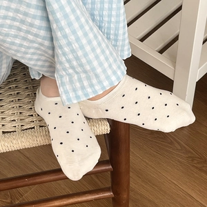 Chaussettes invisibles beiges à pois noirs en coton présentées dans un décor intérieur