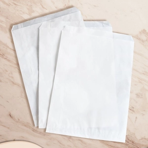 Close-up of three blank white translucent paper bags for spare buttons and accessories