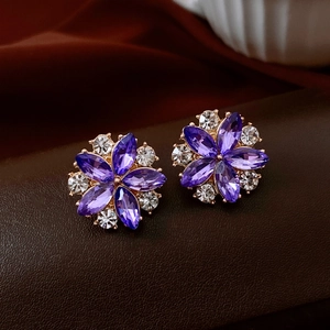 Close-up of floral stud earrings with purple marquise crystals and gold-tone finish