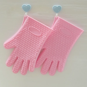 Pink silicone oven mitts with heart-shaped anti-slip texture hanging on white wall