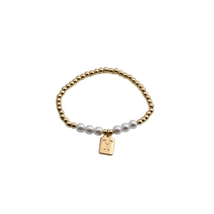 Detailed close-up of a gold beaded bracelet with pearls and a capital letter Y pendant
