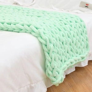 Handgefertigte grob gestrickte Chenille-Decke in Hellgrün, drapiert über ein Bett
