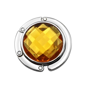 Detail of a portable round handbag hook with a faceted yellow gem and silver frame