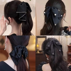 Detail showing various black bow hair clips with pearls on a model in a natural setting