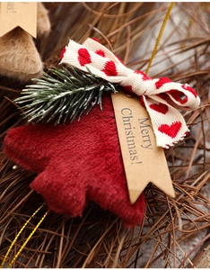 Close-up of red plush Christmas tree ornament with ribbon bow and festive gift tag