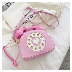 Macro shot of creative pink retro telephone crossbody bag with heart dial detail
