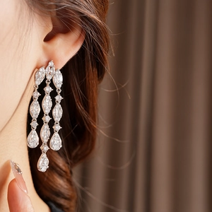Close-up of silver zircon tassel earrings with three-layer drop design on a model