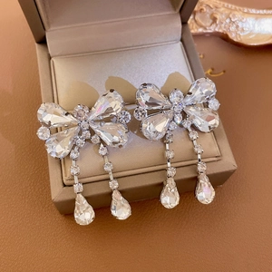 Detail of silver bow earrings with sparkling rhinestones and teardrop crystal fringe