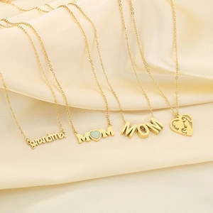 Detail of four gold MOM and heart pendants on silk, featuring opal and silhouette designs
