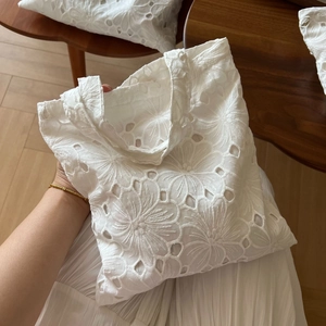 Close-up of intricate hollow flower embroidery on a white cotton canvas tote bag