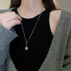 Detailed close-up of a silver spherical pendant necklace on a delicate metal chain