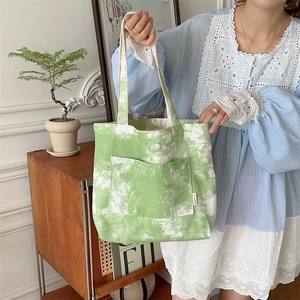 Dettaglio della borsa tote in tela tie-dye verde e bianca con pratica tasca esterna