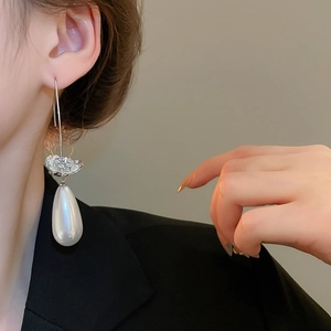 Détail de boucles d'oreilles perles poires avec fleurs en zircon sur modèle