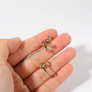 Detail of two pairs of gold birthstone stud earrings with blue and clear crystals