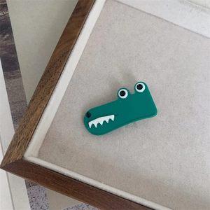 Detail view of a green crocodile hair clip made of acetate on a felt display tray