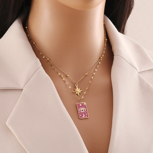 Close-up of layered gold necklace featuring a purple enamel pendant and star moon charms