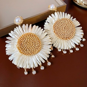 Detailed close-up of Bohemian daisy earrings with raffia petals and rhinestone tassels