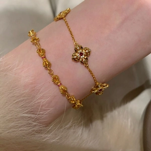 14k gold plated four-leaf clover bracelet with zircon and red stones on model wrist