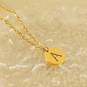 18K gold plated titanium steel necklace with hollow letter A pendant on water ripple surface