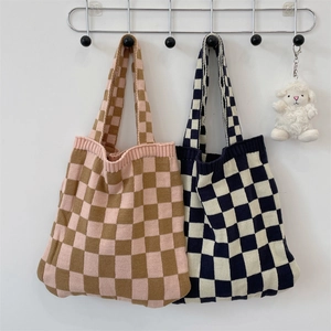 Knit checkerboard tote bags in pink and navy colors hanging on a minimal wall setup