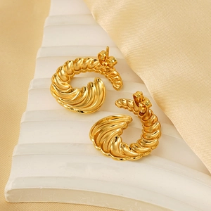 Elegant gold spiral croissant stud earrings on luxury silk background in warm tones