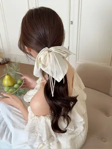 Détail d'un chouchou noeud en satin crème avec perle et longs rubans élégants et fluides