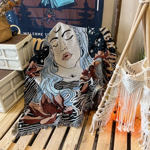 Detail of bohemian woven outdoor blanket with artistic female face and tassel fringe