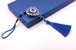 Detailed close-up of blue Turkish Evil Eye heart car charm with tassel on white background