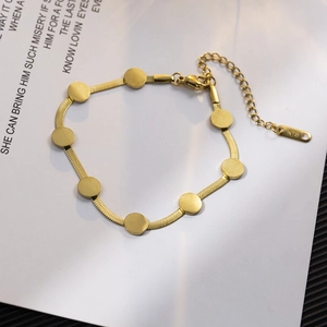 Golden 18K titanium steel snake chain bracelet with round discs on decorative paper