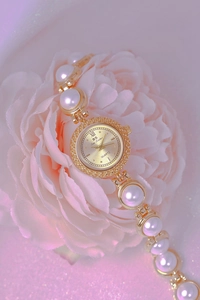 Detail view of gold pearl bracelet watch resting on pink flowers with sharp metal shine