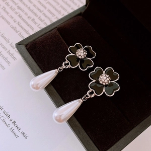 Macro detail of black flower earrings with crystal center and pearl drop in velvet box