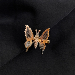 Golden butterfly hair clip with intricate wirework wings on black textured fabric