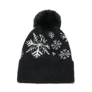 Winter black knit hat with white snowflakes and fluffy faux fur pompom for skiing
