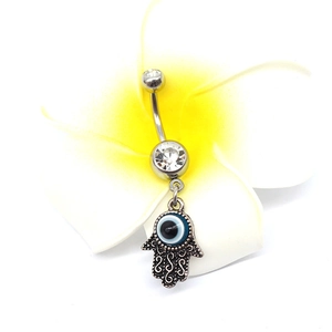 Macro shot of silver belly ring with Fatima Hand pendant and blue evil eye charm