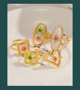 Detailed shot of vintage gold flower rings with heart and geometric resin floral designs