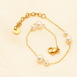 Detail of adjustable stainless steel gold chain bracelet with six white pearls