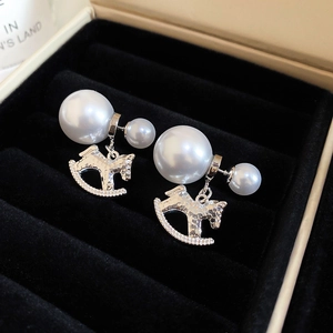 Macro shot of silver horse pearl earrings with hammered texture in a black velvet box