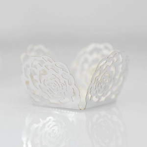 Macro shot of white laser-cut rose hollow paper wrapper for wedding cupcakes and candy