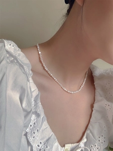Close-up of irregular baroque freshwater pearl necklace worn with lace shirt