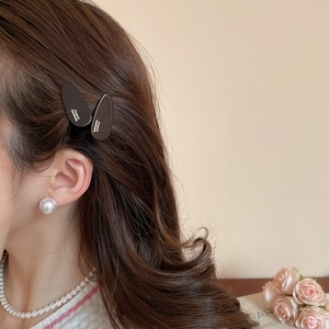 Détail de la pince à cheveux goutte marron mat portée avec des perles élégantes