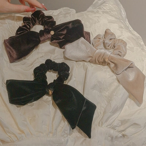 Elegant velvet bow scrunchies in brown, black, and beige colors on soft fabric