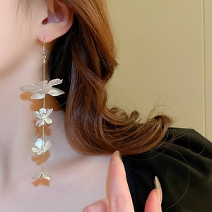 Elegant gold fringe earrings with four white cascading flowers worn by a model