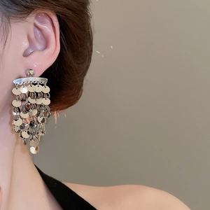 Close-up of long silver sequin tassel earrings with multi-layer round polished disks