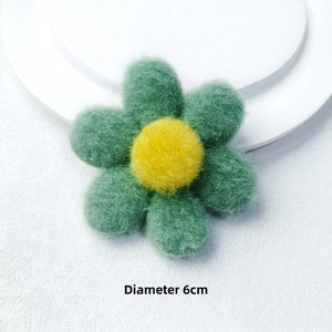 Detailed macro view of a 6cm handmade wool felt flower in green and yellow for DIY crafts
