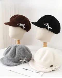 Detail view of wool octagonal caps in four colors featuring side bow and leather patch