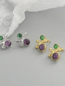 Gros plan de boucles d'oreilles géométriques avec pierres vert émeraude et violettes
