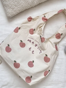 Canvas tote bag with sweet peach prints and Japanese text on white wrinkled fabric