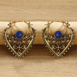 Close-up of bohemian heart-shaped gold drop earrings with turquoise stone inlay