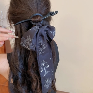Détail d'un pic à cheveux noir vintage avec ruban en soie floral et pompon élégant